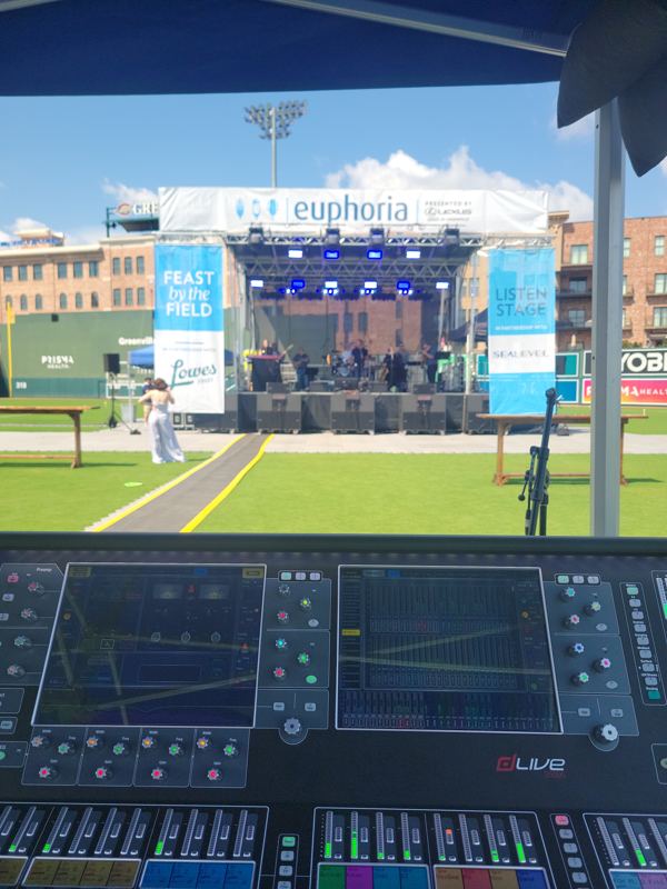 Outdoor stage at a ballpark seen from behind the mixing console