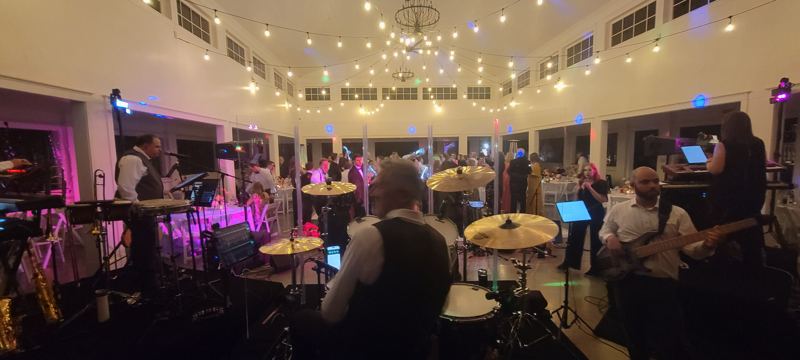 Band playing in a ballroom with chandeliers and uplighting