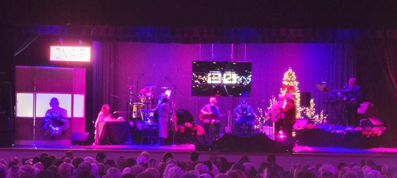 Christmas stage with a tree, band, and video screen