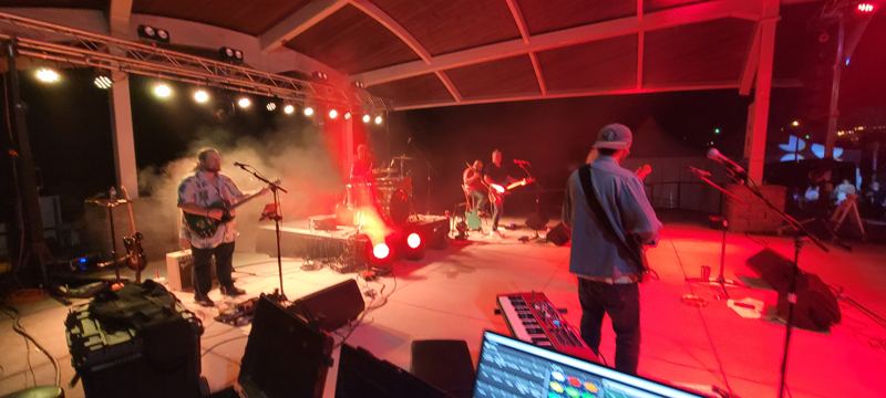 Band playing under a pavilion in red and amber light