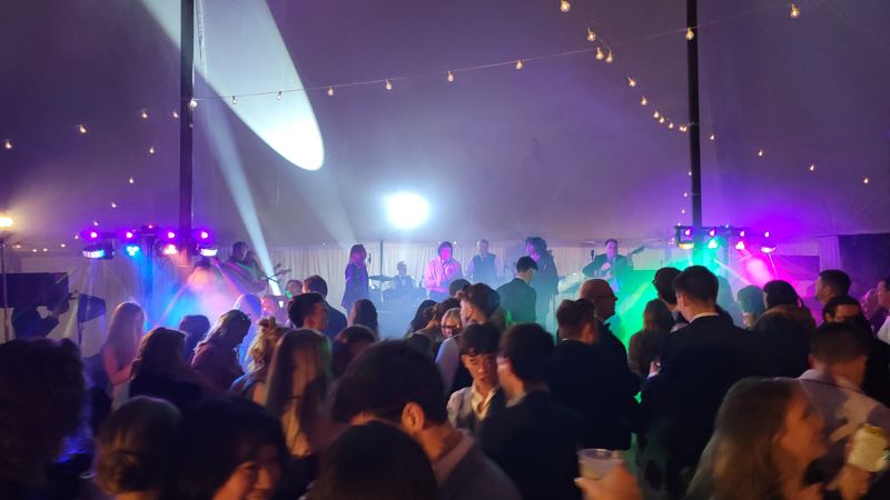 Crowded dance floor in a tent with moving-head beams and colored wash