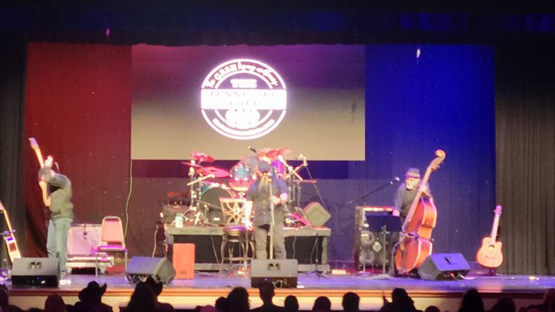 Theater stage with a band and a projected logo on the screen